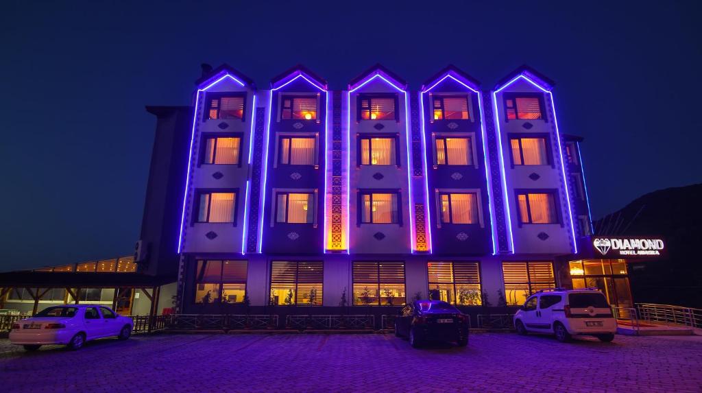 un edificio iluminado de azul con coches aparcados delante en Amasra Diamond Hotel, en Amasra