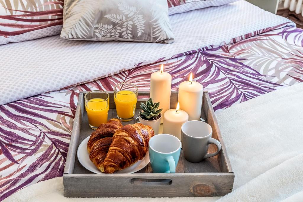 ein Tablett mit Speisen mit Kerzen und Croissants auf dem Bett in der Unterkunft Cosy 2 pièces aux Portes de Paris in Clichy