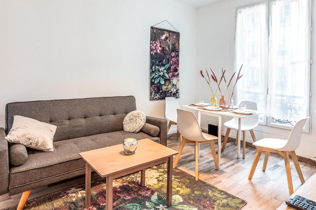 ein Wohnzimmer mit einem Sofa und einem Tisch in der Unterkunft Cosy 2 pièces aux Portes de Paris in Clichy