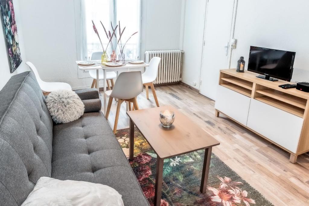 ein Wohnzimmer mit einem Sofa und einem Tisch in der Unterkunft Cosy 2 pièces aux Portes de Paris in Clichy
