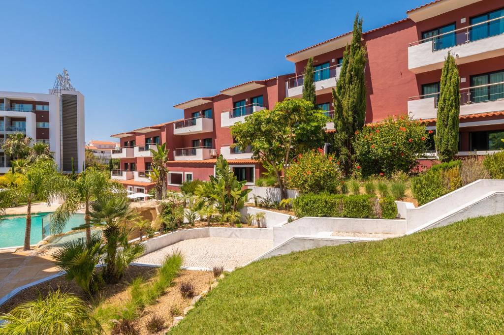 an apartment building with a garden and a swimming pool at Topazio Vibe Beach Hotel & Apartments - Adults Friendly in Albufeira