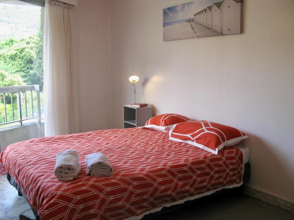 - une chambre avec un lit doté de draps rouges et blancs et une fenêtre dans l'établissement La résidence du port, à Nice