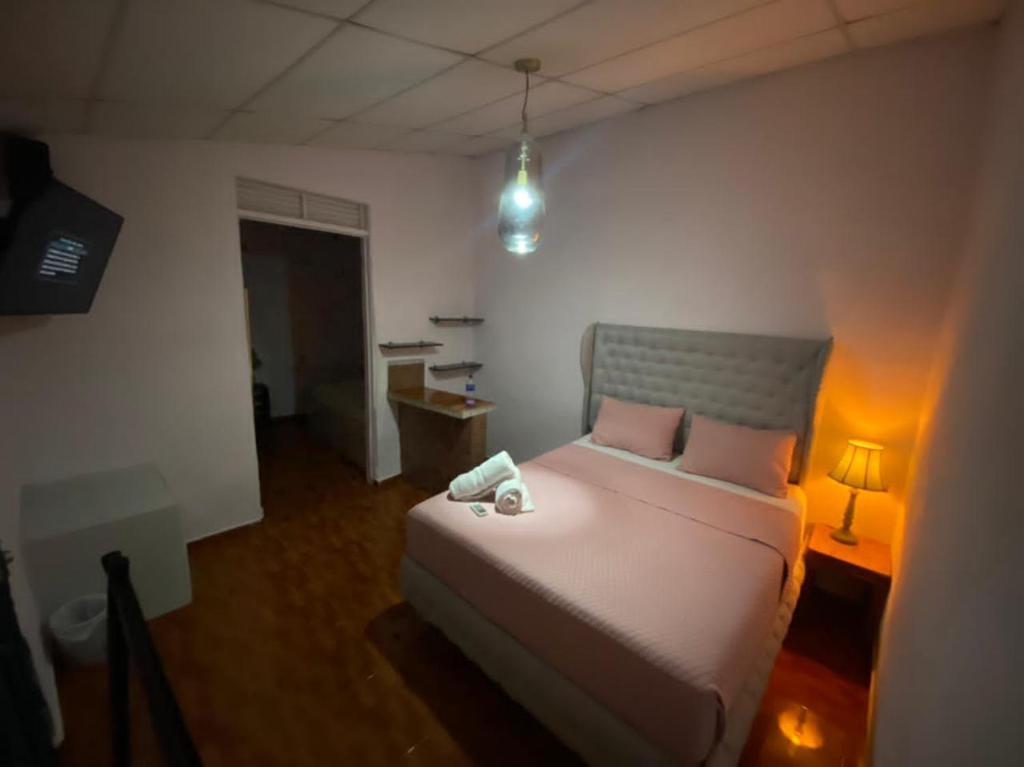 1 dormitorio con cama, escritorio y lámpara en Velvet Hostal La novena en Santa Ana