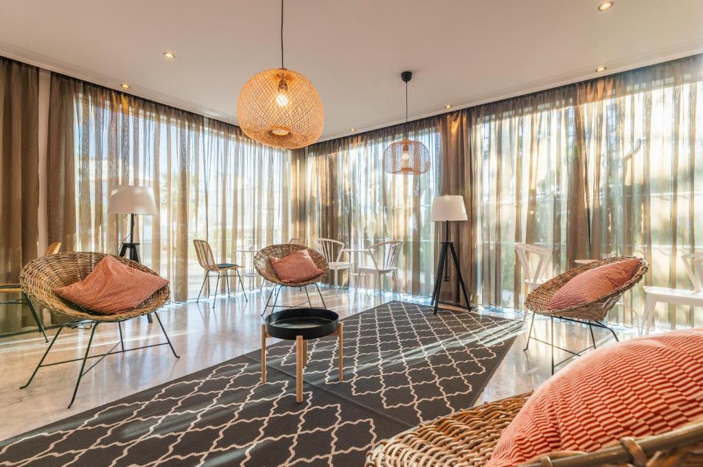 a living room with chairs and tables and windows at Topazio Vibe Beach Hotel & Apartments - Adults Friendly in Albufeira