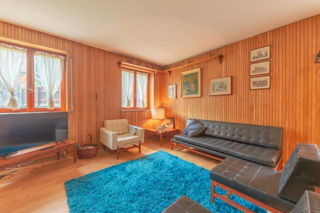 a living room with a black leather couch and a blue rug at Appartamento Camille in Courmayeur