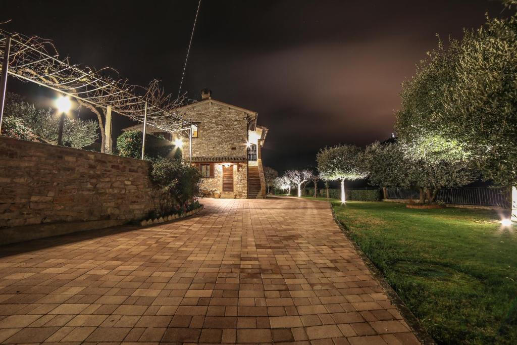 un camino de ladrillo que conduce a un edificio por la noche en La Casa Tra Gli Ulivi, en Asís