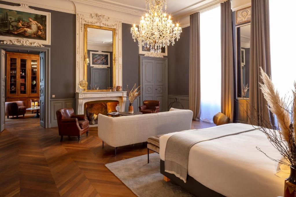 a bedroom with a bed and a fireplace and a chandelier at Margaret - Hôtel Chouleur in Nîmes