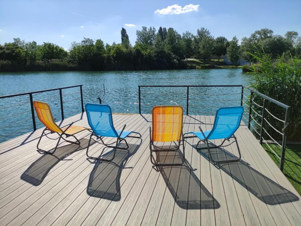 tres sillas sentadas en un muelle junto al agua en Apartments Relax, en Dunajská Streda