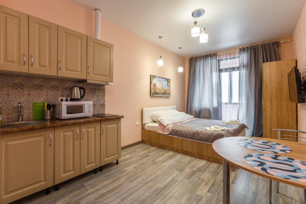 モスクワにあるFoRRest Vodnyのベッド1台、キッチン(テーブル付)が備わる小さな客室です。