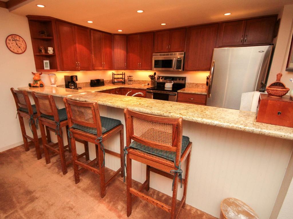 a kitchen with a counter with chairs and a refrigerator at Mountainback #111 in Mammoth Lakes