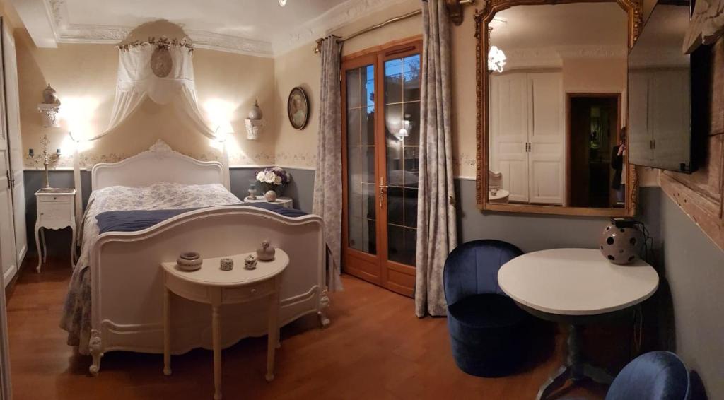 1 Schlafzimmer mit einem Bett, 2 Tischen und einem Spiegel in der Unterkunft La Marlottine in Bourron-Marlotte