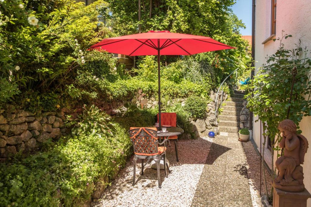 a table with a red umbrella in a garden at Haus Sonnenschein Gartentraum in Bermatingen