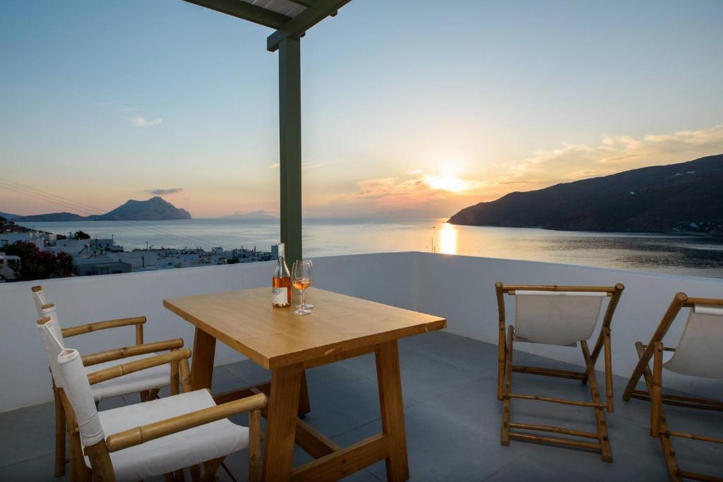 una mesa y sillas en un balcón con vistas a la puesta de sol en Theasis Suites, en Amorgós