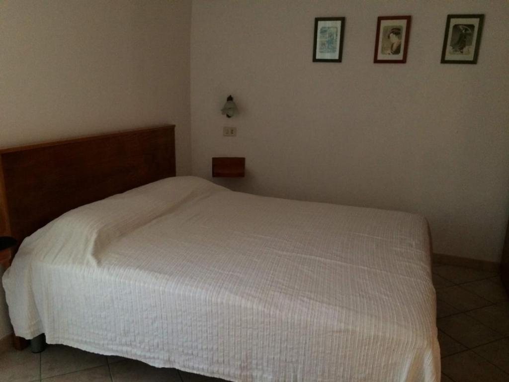 białe łóżko w sypialni z dwoma zdjęciami na ścianie w obiekcie Casa torvaianica w mieście Torvaianica