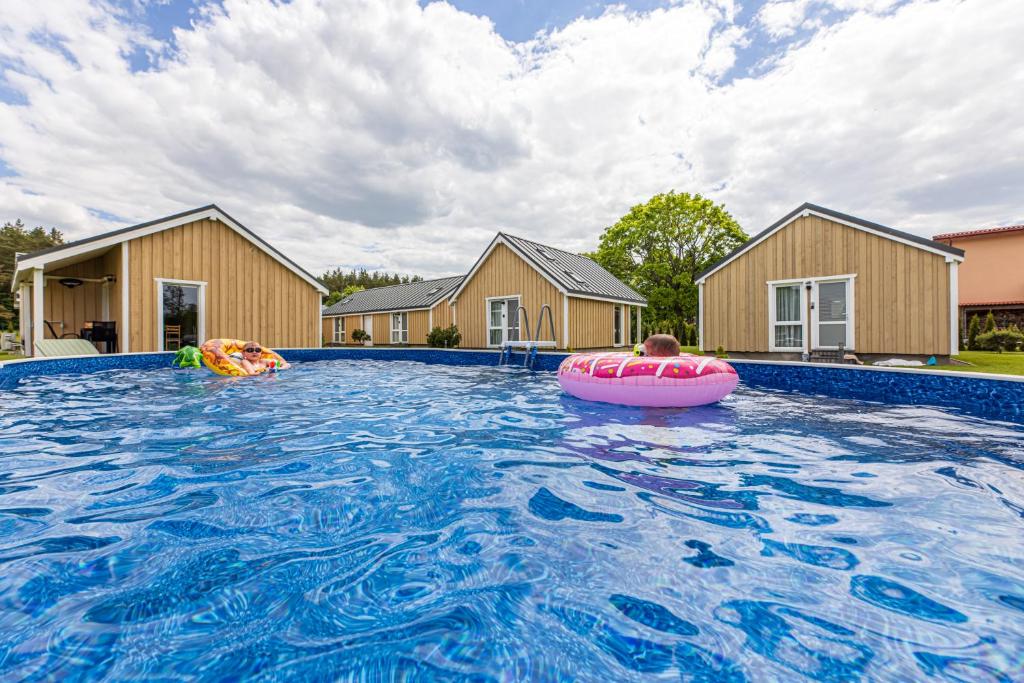 a man in a pool with a pink raft in the water at Atostogų Medis in Šventoji