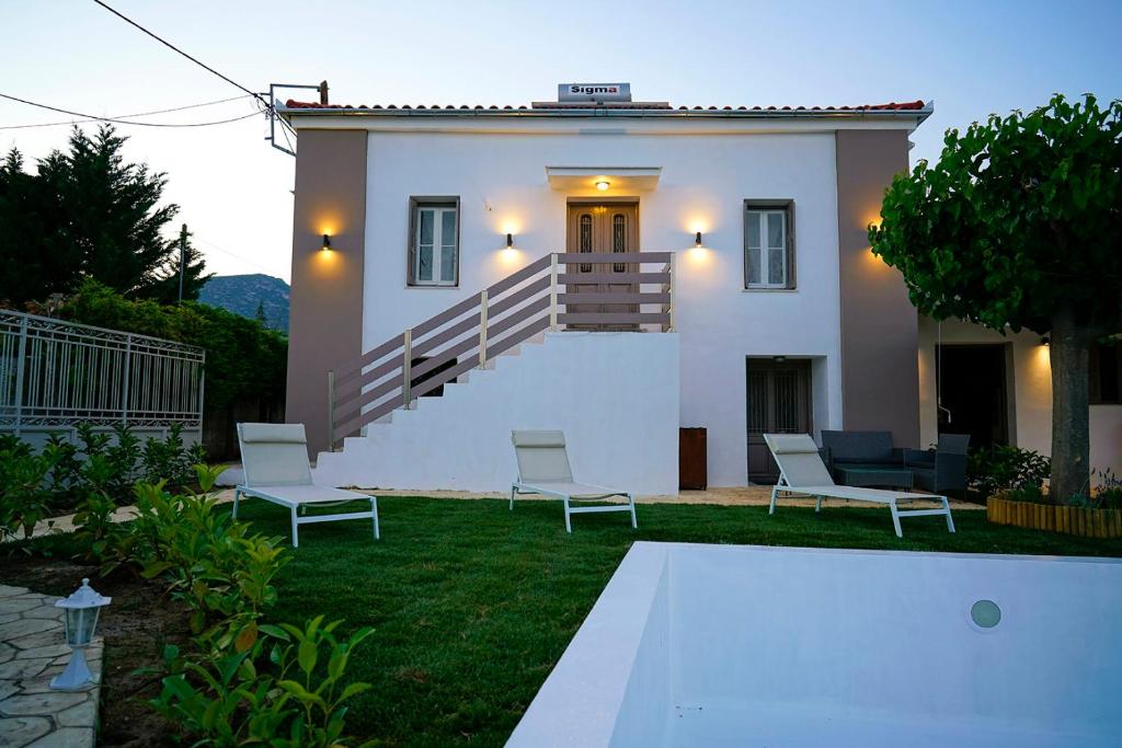 a white house with two chairs and a staircase at Charikleia's country house in Pelion in Volos