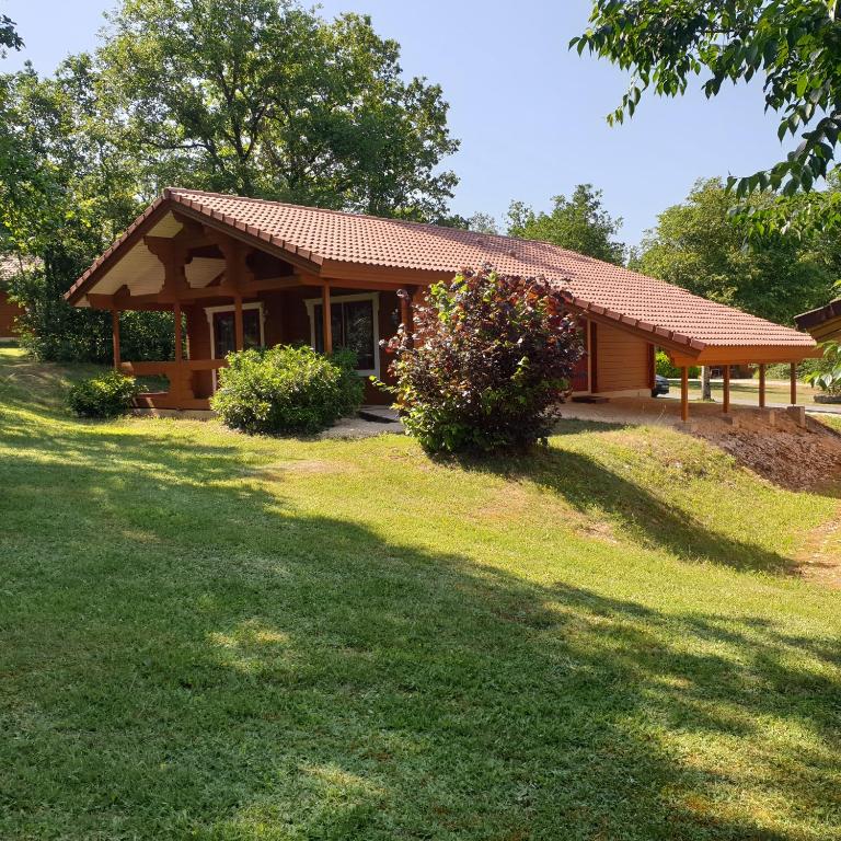 une petite maison avec une cour en gazon devant elle dans l'établissement Charmant Chalet LE DAMELI, Village du Soleil, Chalet 61, à Mauroux