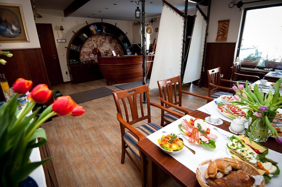 une salle à manger avec une table, de la nourriture et des fleurs dans l'établissement Willa Anna, à Gdynia