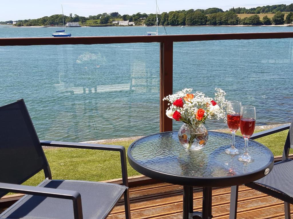 una mesa con 2 copas de vino y flores en el balcón en Delfryd, en Y Felinheli