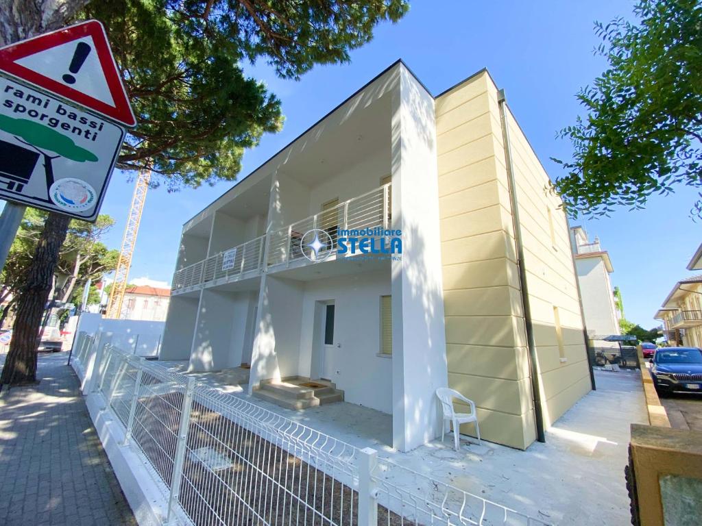 a small white building with a sign on a street at Condominio Rossella in Lido di Jesolo