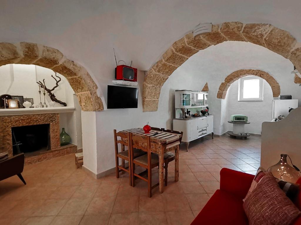 een woonkamer met een tafel en een keuken met bogen bij I Trulli dell'Orfanello in Martina Franca