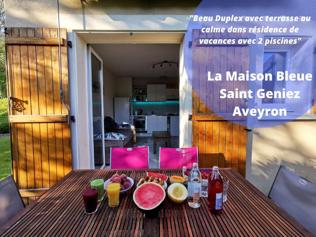 una mesa de madera con comida y bebidas. en Au 11 T3 duplex, village vacances, piscines, parking, en Saint-Geniez-dʼOlt