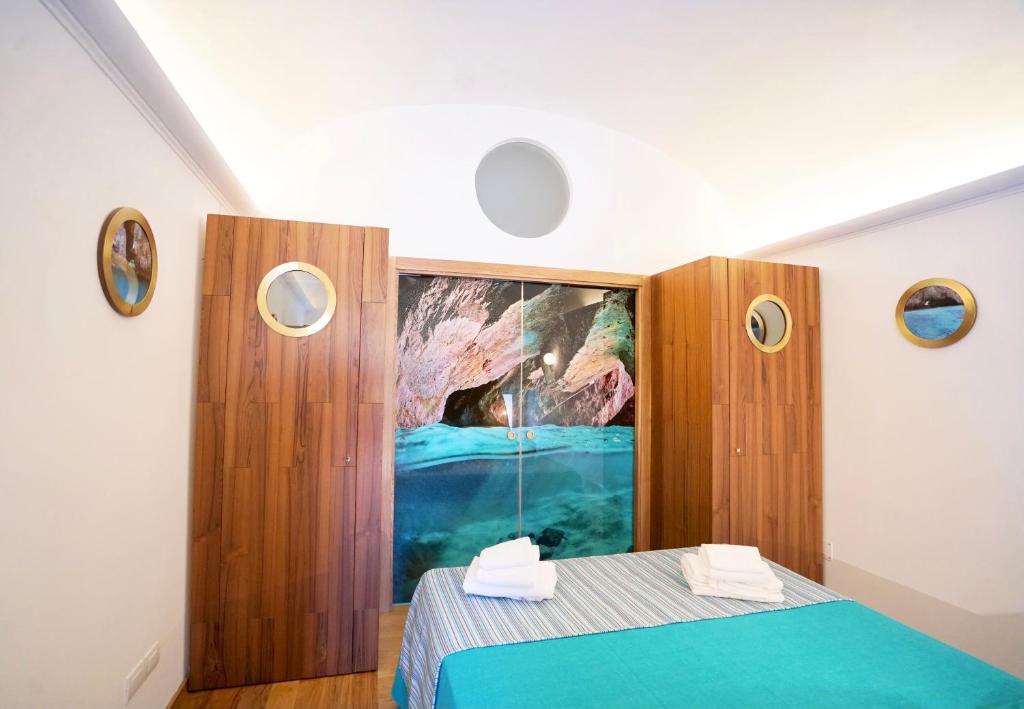 a bedroom with a blue bed and a painting on the wall at Grotta Verde Luxury Suite by CapriRooms in Capri