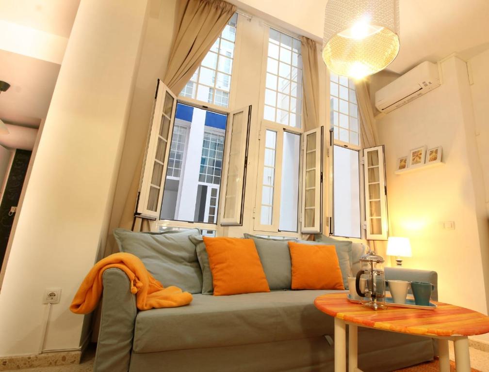 sala de estar con sofá verde y ventanas en Apartamento Pastora Sevilla, en Sevilla