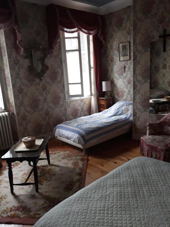 a bedroom with two beds and a table and a window at Chez Virginie in Lourdes