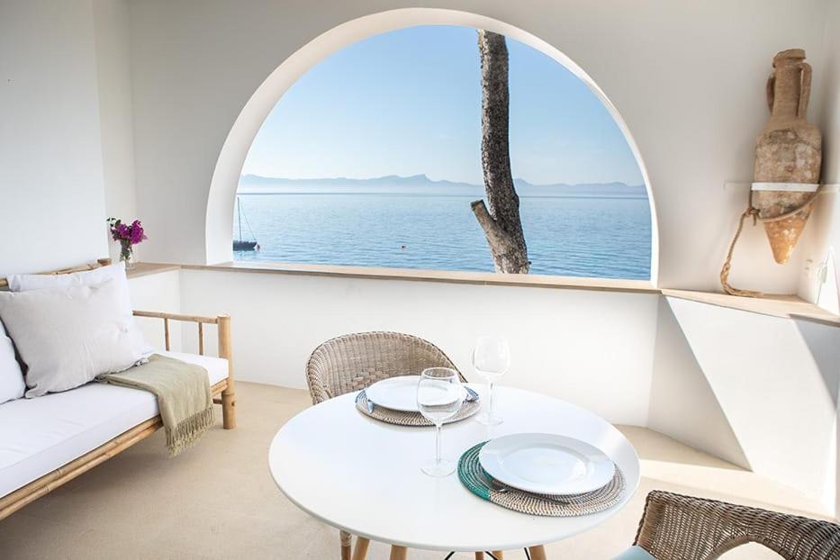 a white living room with a table and a window at ALCUDIA-VIDA SANA-PRIMERA LINEA DE MAR in Alcudia