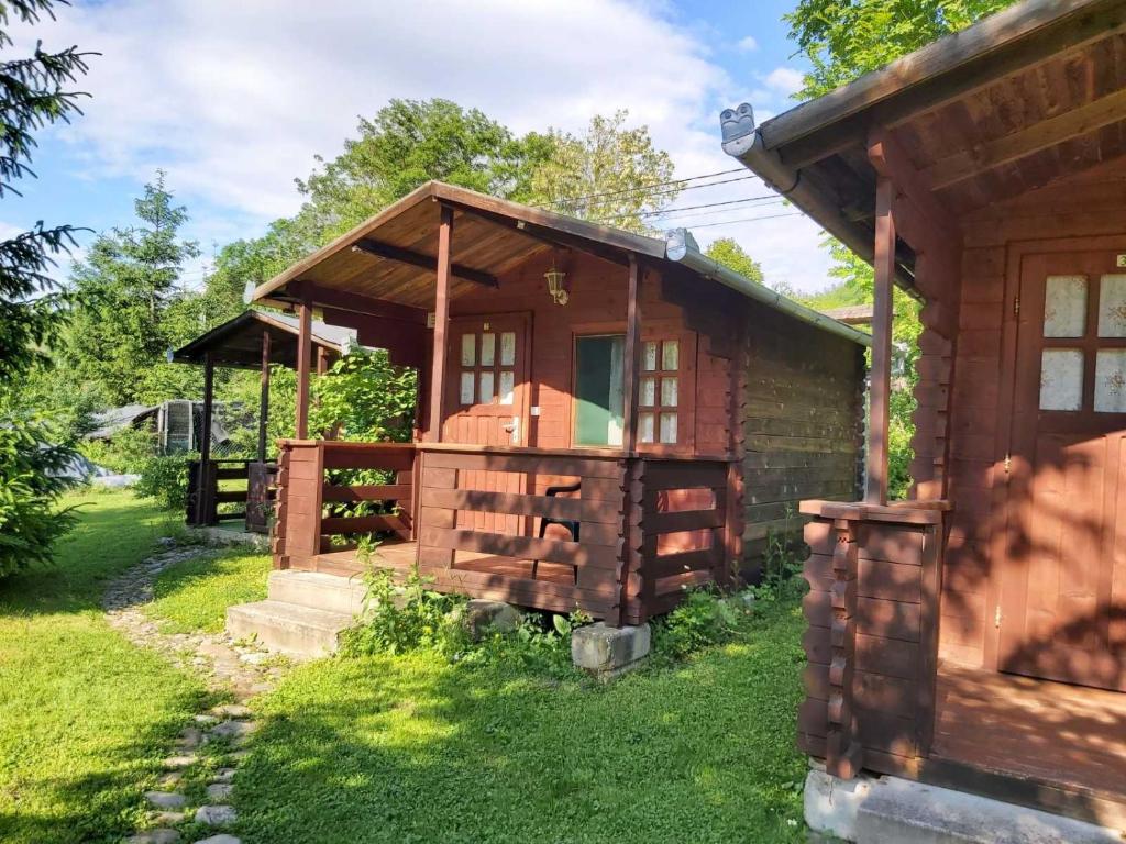 Cabaña de madera con porche y césped verde en Bungalow Camping Edelweiss - Floare de colt - Gyopár, en Rimetea