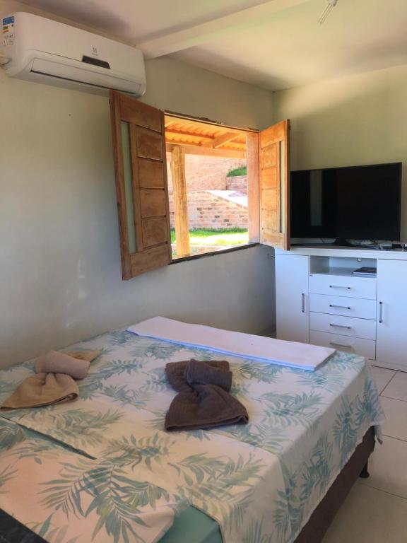 een slaapkamer met een bed, een televisie en een raam bij Barbosa acomodações. Lencois-BA in Lençóis