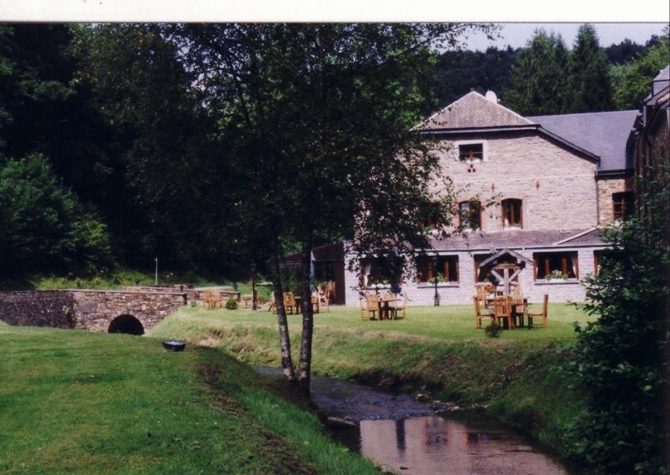 a house with a table and a river in front of it at Hotel Le Moulin Simonis in Laforêt