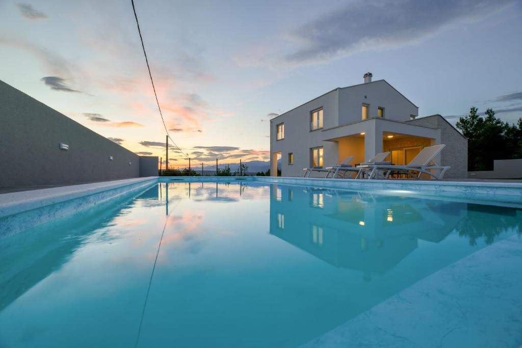 a villa with a swimming pool in front of a house at NEW Villa Buterin with heated pool in Novigrad Dalmatia