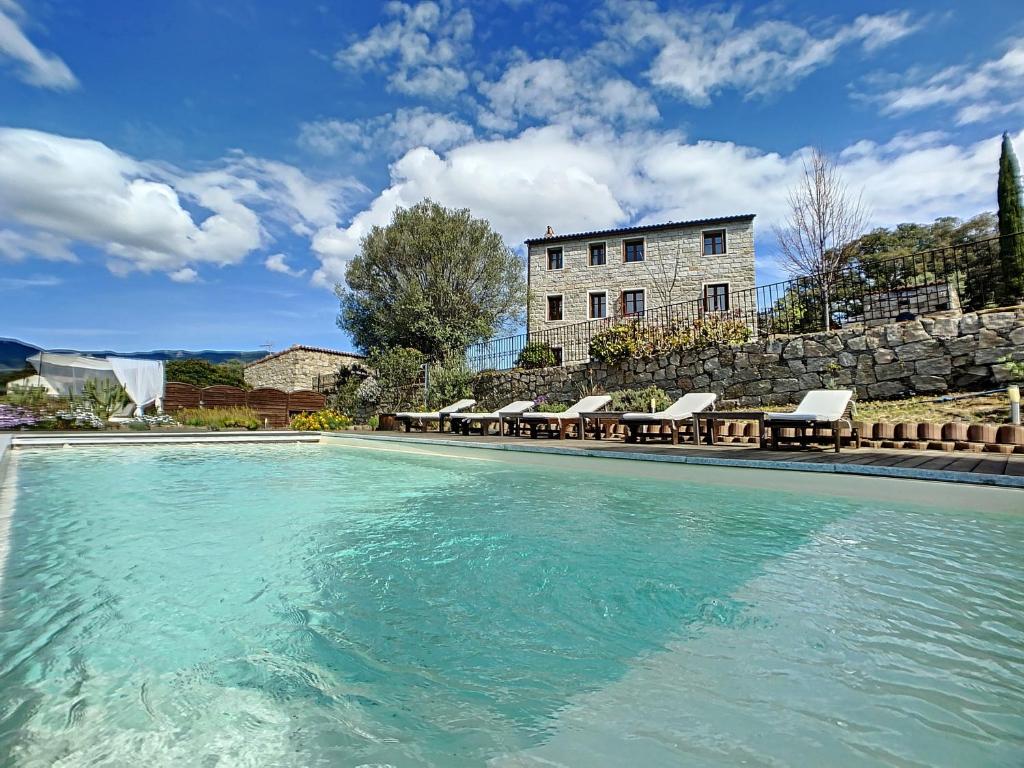 una piscina con sedie e un edificio sullo sfondo di Domaine de Tappa - Casa Filicina a Sollacaro