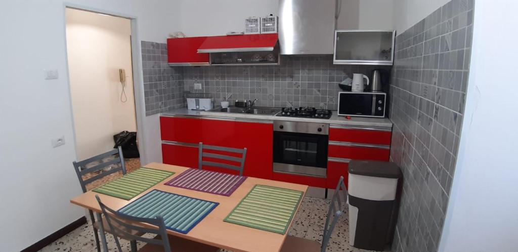 a kitchen with a wooden table and red cabinets at GAIA Accommodation in Alghero