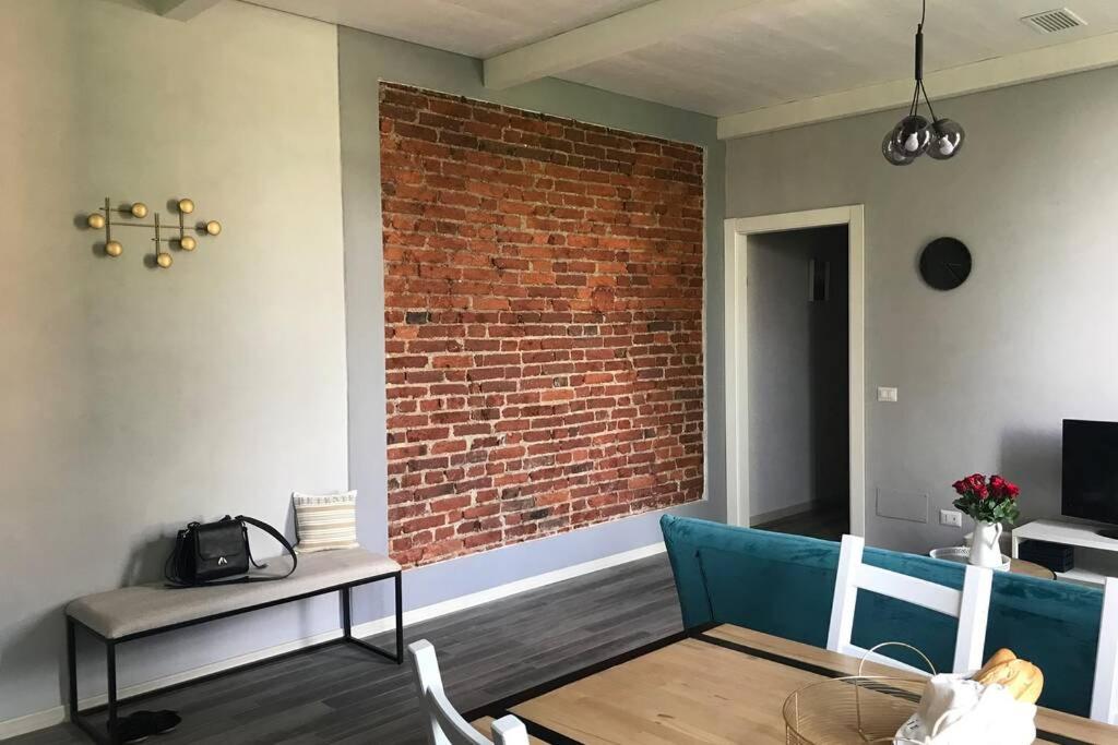 uma sala de estar com uma parede de tijolos e um sofá azul em Mazzini apartment em Arona