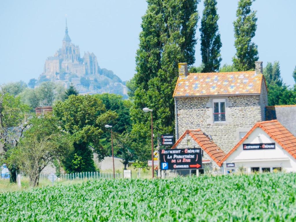 una casa in un campo con un castello sullo sfondo di La Parenthèse de la Baie a Courtils