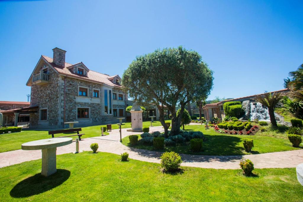 a park in front of a building with a tree at Hotel Rural Finca Aldeola in Malpica