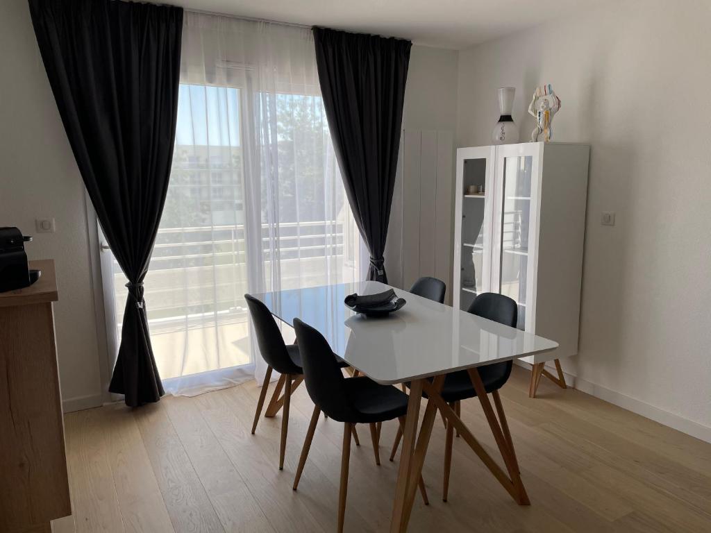 - une table à manger et des chaises dans une pièce avec fenêtre dans l'établissement Appartement T2 les minimes chic et cosy, à La Rochelle