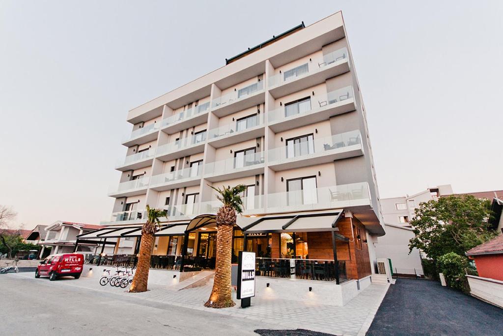 a large building with palm trees in front of it at Hotel Hills Ulcinj in Ulcinj