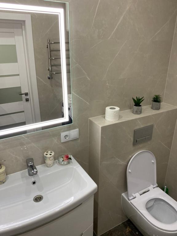 uma casa de banho com um lavatório, um WC e um espelho. em Люкс Апартаменты в центре города ,ЖК Театральный em Rivne