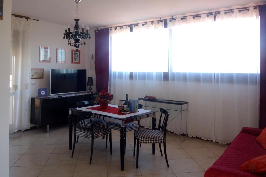 sala de estar con mesa, sillas y TV en Borgo degli Ulivi en Alghero