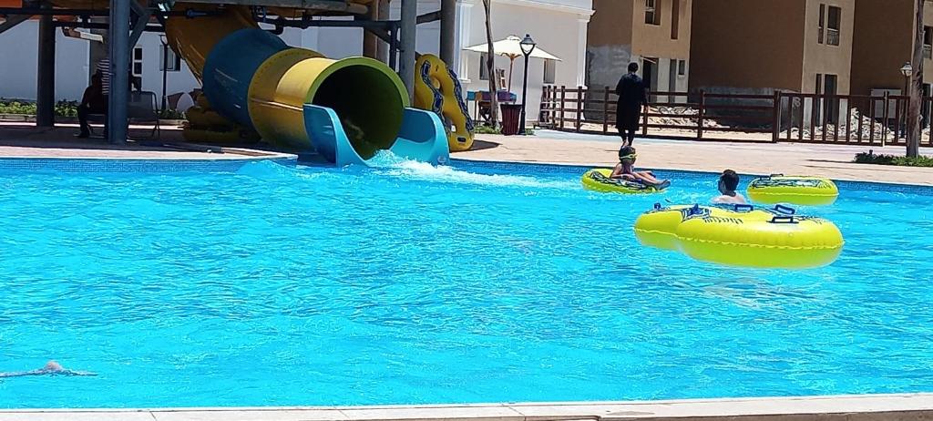 a pool with two people in a water slide at الكيلو 91-اكوا فيو aqua view للمصرين فقط in Abû Zeira