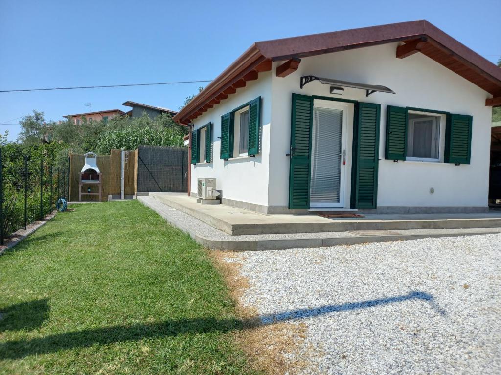 une petite maison avec des volets verts et une cour dans l'établissement Bilo Francesca e Massimo, à Castelnuovo Magra