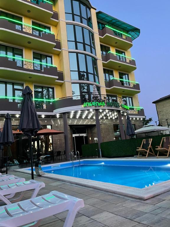 un hotel con piscina frente a un edificio en Hotel Condori, en Kobuleti