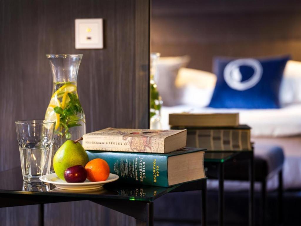 a table with books and fruit on a table in a hotel room at Hotel Logos Kraków in Krakow