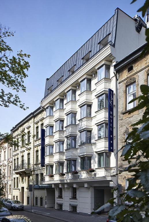 a large white building with a blue sign on it at Hotel Logos Kraków in Krakow