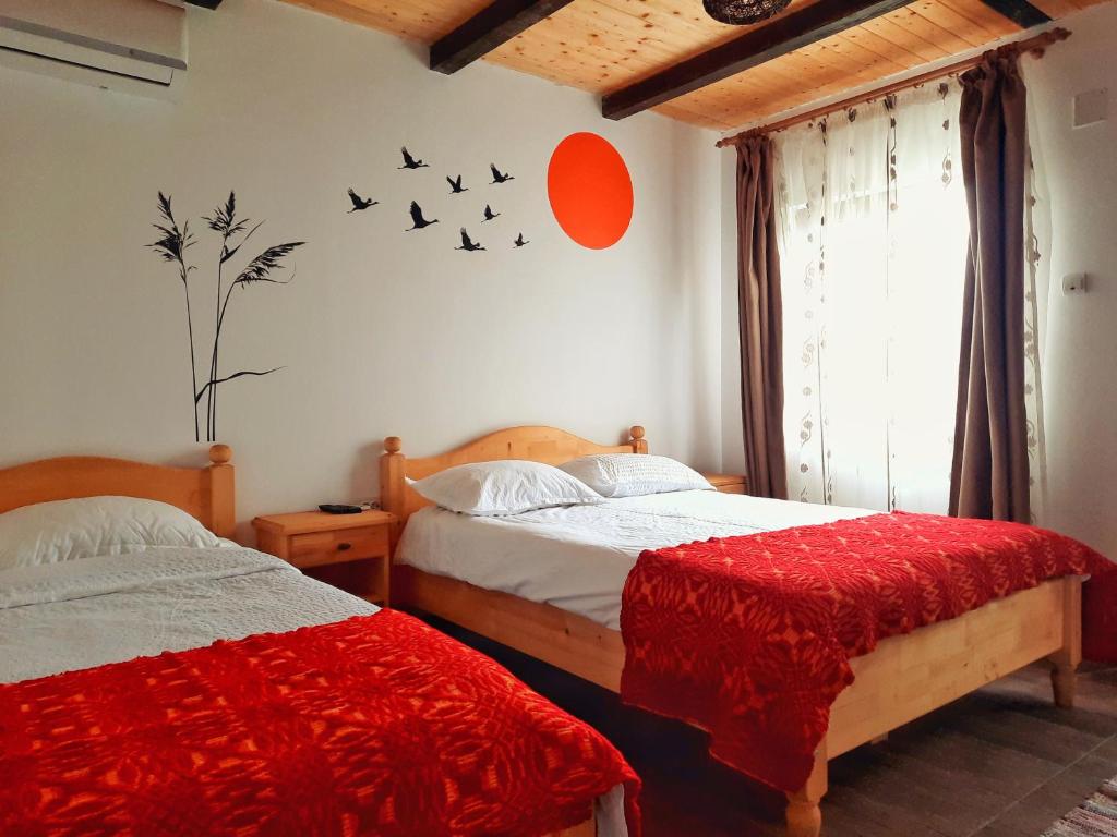 ムリギオルにあるCasa din Deltaのベッドルーム1室(ベッド2台付)、壁に鳥が描かれた窓が備わります。