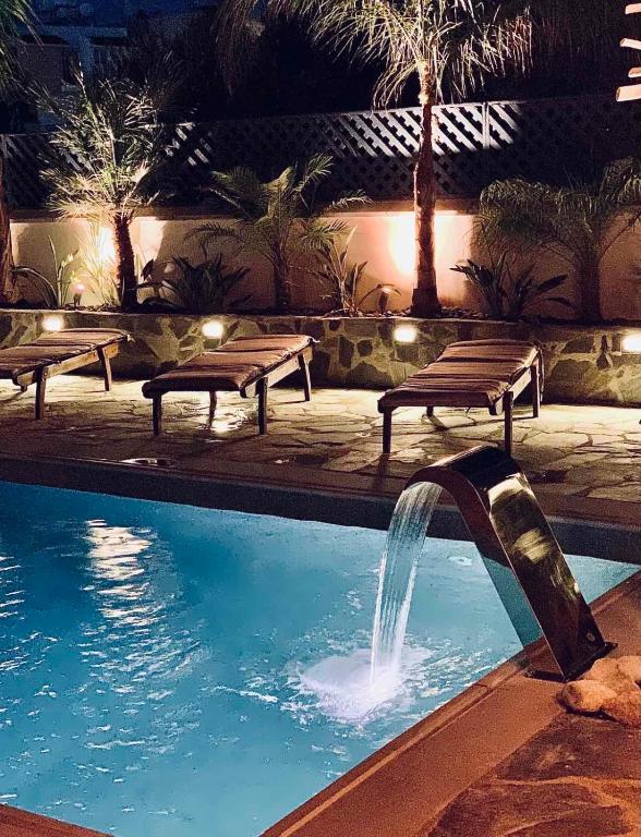 a swimming pool with benches and a water fountain at Harmonia Blue Mediterranean Modern Luxury HEATED POOL Prime Location in Polis Chrysochous